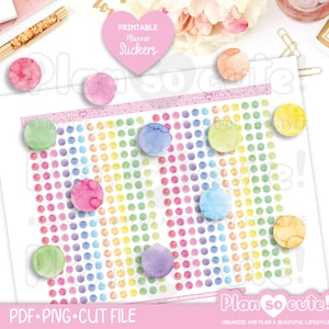 Op de afbeelding: Een vel met printbare plannerstickers met een regenboogstippenpatroon. De stickers zijn in verschillende aquarelkleuren, met een roze hartvormige sticker met de tekst "Printable Planner Stickers". De tekst "Plan so cute!" is ook zichtbaar.