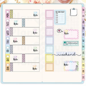 Pu&ograve; includere: Un planner settimanale con adesivi colorati che presentano la parola "keto" e altre frasi motivazionali. Il planner ha un layout a griglia con i giorni della settimana e i mesi dell'anno etichettati.