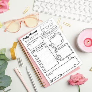Puede incluir: Un planificador diario rosa con la frase "Daily Planner" en la parte superior. Incluye secciones para objetivos y citas. La imagen tambi&eacute;n muestra gafas rosas, un teclado, una vela y flores.
