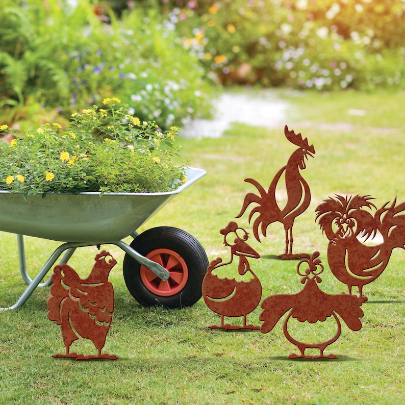 May include: A set of six metal garden decorations shaped like chickens and a rooster. The decorations are rusty brown in color and have a whimsical, cartoonish style. They are placed on a green lawn in front of a wheelbarrow.