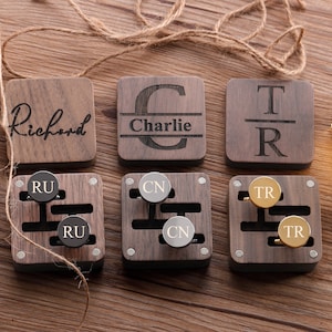 Puede incluir: Seis cajas de madera con nombres grabados: "Richard", "Charlie", "TR", "RU", "CN" y "TR". Cada caja contiene dos gemelos con iniciales grabadas.