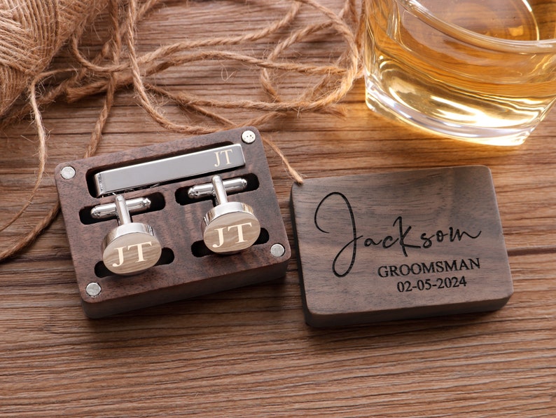 Puede incluir: Una caja de madera con un clip para corbata y gemelos grabados con las iniciales "JT". Una placa de madera separada est&aacute; grabada con el nombre "Jackson", la palabra "Groomsman" y la fecha "02-05-2024".