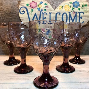 Puede incluir: Conjunto de cinco copas de vino de vidrio morado con un diseño texturizado. Las copas tienen una copa ancha y un tallo largo.