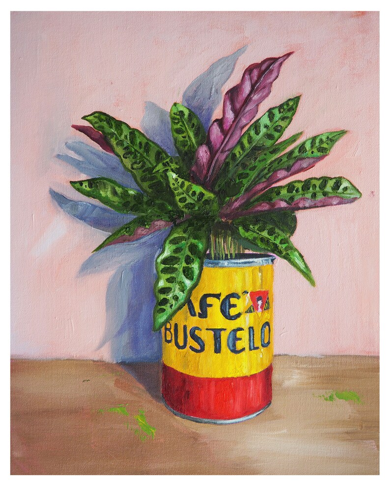 Puede incluir: Una pintura de una planta verde y morada en una lata amarilla y roja con el texto "Cafe Bustelo" en ella.