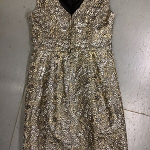 May include: A sleeveless gold and silver brocade dress with a V-neckline and a back zipper closure.