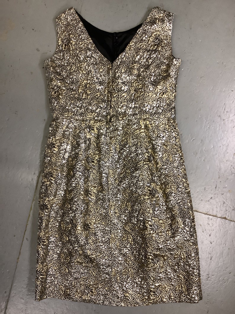May include: A sleeveless gold and silver brocade dress with a V-neckline and a back zipper closure.