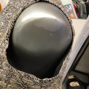 May include: A sleeveless dress with a black and gold floral pattern. The dress is made of a shiny fabric and has a fitted bodice.