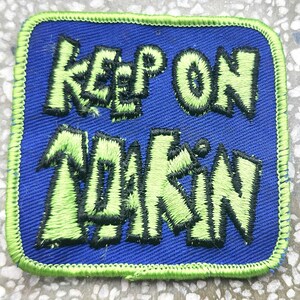 May include: A blue and green embroidered patch with the text "Keep on Truckin'" in a stylised font.