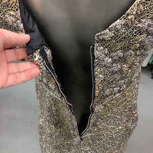 May include: A gold and silver metallic dress with a zipper down the back.