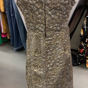 May include: A gold and silver brocade sleeveless dress with a V-neckline and a back zipper closure.