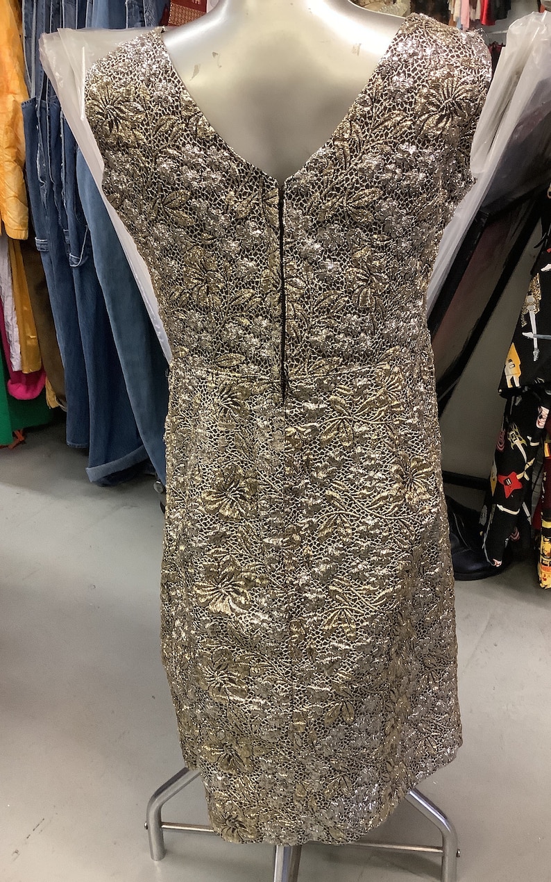 May include: A gold and silver brocade sleeveless dress with a V-neckline and a back zipper closure.