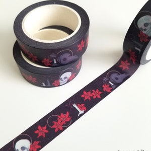 May include: Black washi tape with a repeating pattern of red flowers, skulls, and candles. The tape is rolled up and ready to be used.