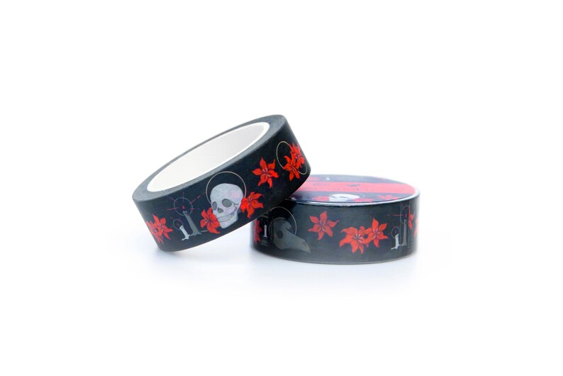 May include: Two rolls of black washi tape with a repeating pattern of red flowers, skulls, and a plague doctor mask.