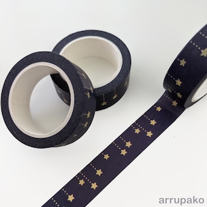 May include: Two rolls of navy blue washi tape with a gold star pattern. The tape is unrolled and shows the pattern.