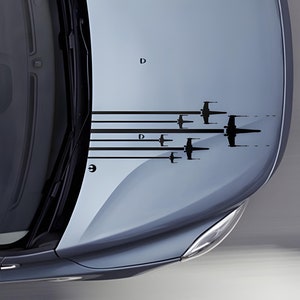 Puede incluir: Un coche gris con una calcomanía de caza X-Wing negra en el capó. La calcomanía presenta múltiples X-Wings volando en formación. El texto "X-Wings for Cars" está en la parte superior de la imagen. El texto "© 2017 ThePatternsFactory" está en la parte inferior de la imagen.