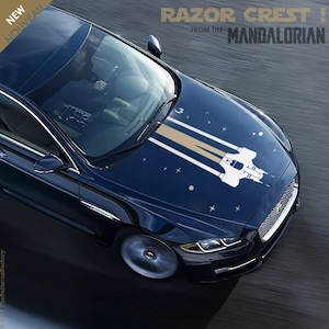 Peut inclure: Une voiture bleue avec un autocollant Razor Crest blanc et or sur le capot. L'autocollant est tiré de la série télévisée The Mandalorian. Le texte "RAZOR CREST! FROM THE MANDALORIAN" est en haut de l'image.