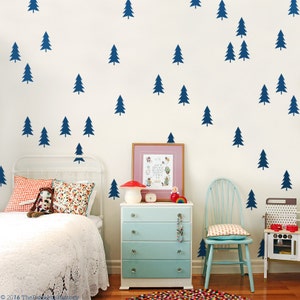 Peut inclure: Une chambre à coucher blanche avec un lit blanc, une commode bleue, une chaise bleue et un mur blanc avec des autocollants d'arbres bleus. Le mur a le texte "ARCH ESPOIR FOREST" sur un cadre rose.