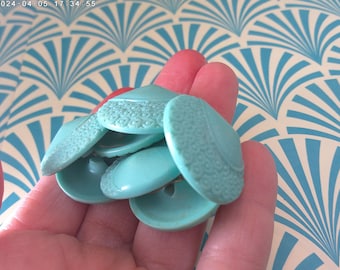 Könnte beinhalten: Eine Gruppe türkisfarbener Plastikknöpfe mit einem strukturierten Design. Die Knöpfe sind rund und haben eine erhabene Mitte.