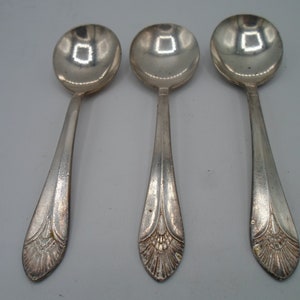 May include: Three silver spoons with ornate handles. The spoons have a rounded bowl and a decorative design on the handle.