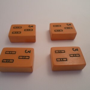May include: Four orange dominoes with black dots. Each domino has three dots on one side and three dots on the other side.