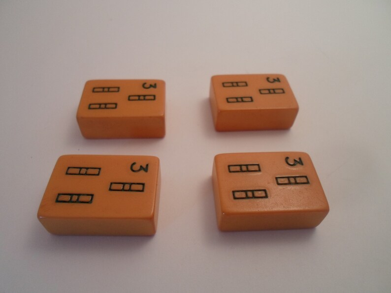 May include: Four orange dominoes with black dots. Each domino has three dots on one side and three dots on the other side.