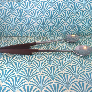 May include: Two serving spoons with brown handles and silver spoon heads. One spoon is a serving spoon, and the other is a serving fork. The spoons are on a blue and white patterned surface.