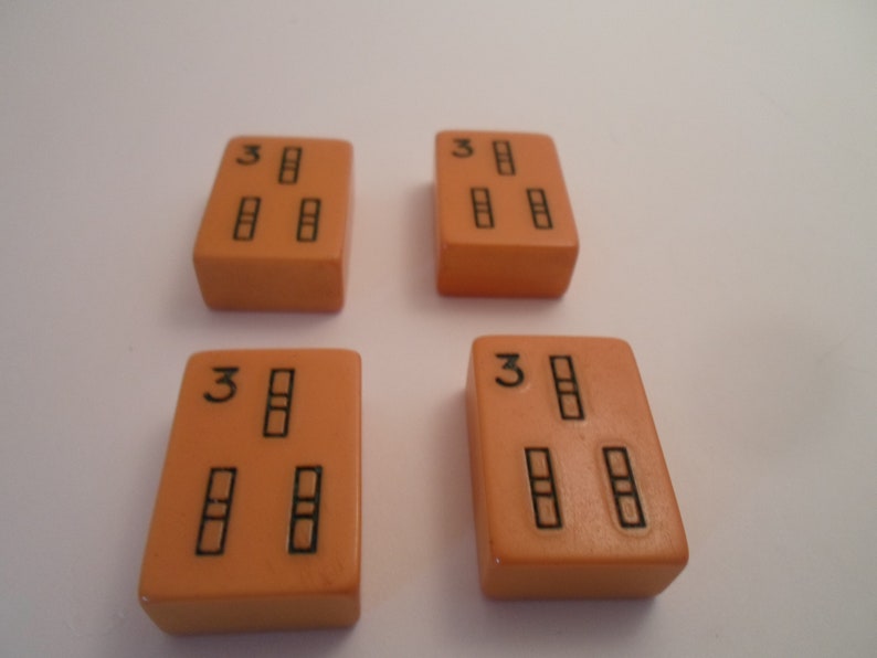 May include: Four orange dominoes with black dots. Each domino has three dots, arranged in a vertical line with the number "3" at the top.