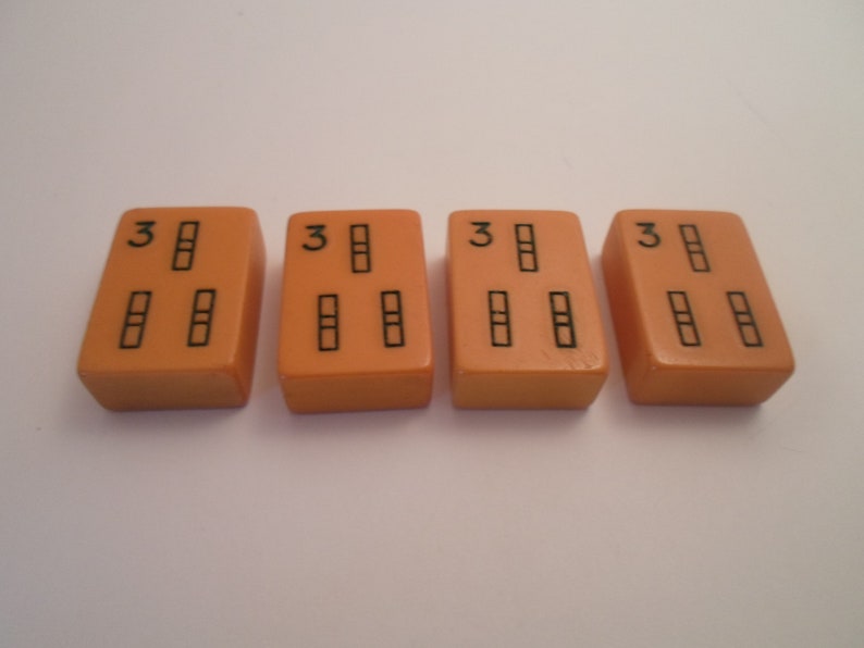 May include: Four orange dominoes with black dots. Each domino has the number "3" on one end and three dots on the other end.