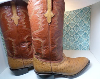 May include: A pair of brown leather cowboy boots with ostrich skin detailing. The boots have intricate stitching and a pointed toe.