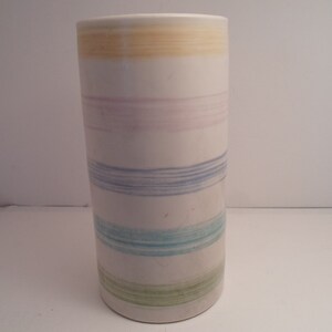 May include: A white ceramic vase with a striped design in shades of yellow, pink, blue, and green.