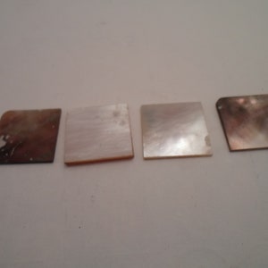 May include: Four square pieces of mother of pearl shell, two are white and two are brown with white marbling.