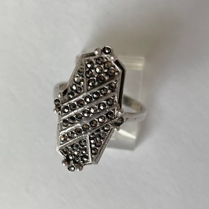 Op de afbeelding: Een zilveren ring met een geometrisch ontwerp bezet met zwarte marcasietstenen.