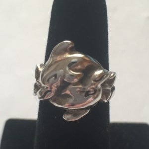 May include: A silver ring featuring two dolphins intertwined, with a smooth, polished finish.