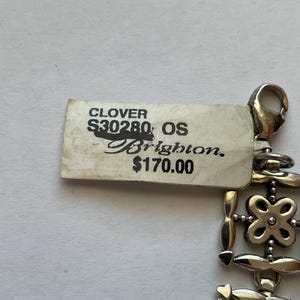 以下が含まれることがあります： クローバーのデザインのシルバーブレスレット。ブレスレットに付けられたタグには、「CLOVER S30280 OS Brighton 170.00ユーロ」と記載されています。