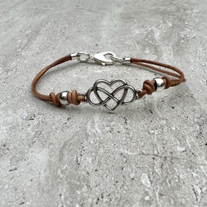 May include: A brown leather bracelet with a silver infinity heart charm and silver beads.