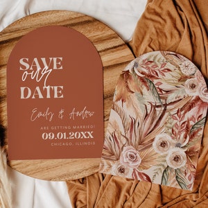 May include: Save the date card with a terracotta arch design. The text reads "Save our date" in white with a stylized font. The names "Emily & Andrew" are written in cursive below the text. The date "09.01.20XX" is written in white below the names. The text "Chicago, Illinois" is written in white below the date.