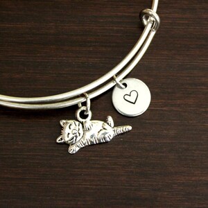 May include: Silver expandable bracelet with a charm of a cat and a charm with a heart engraved on it.