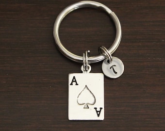 May include: Silver keychain with a charm of the ace of spades playing card and a small charm with the letter T.