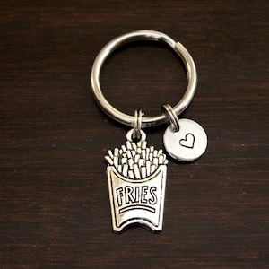 May include: Silver keychain with a charm of a french fry container with the word "FRIES" on it and a small heart charm.