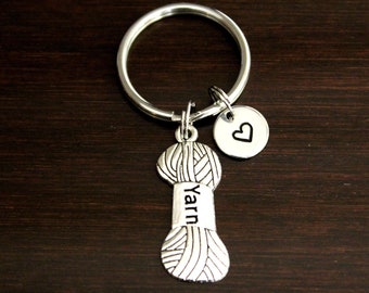 May include: Silver keychain with a yarn ball charm and a small heart charm. The yarn ball charm has the word "yarn" engraved on it.