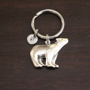 May include: Silver polar bear keychain with a silver keyring and a small silver charm with the letter "R" engraved on it.