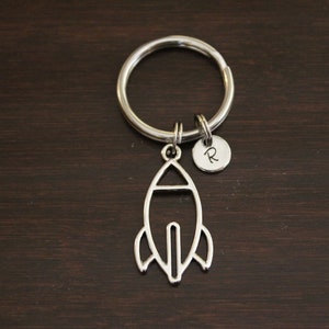 May include: Silver rocket ship keychain with a small silver charm with the letter "R" engraved on it.