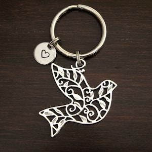 May include: Silver-toned key chain with a small heart charm and a larger charm shaped like a stylized dove with a filigree design.