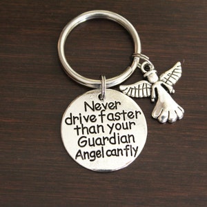May include: Silver keychain with a round charm that reads "Never drive faster than your Guardian Angel can fly" and a small angel charm.