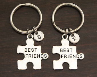 May include: Two silver keychains with puzzle piece charms that say "Best Friends" and initial charms.