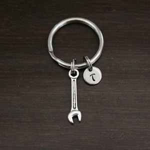 May include: Silver keychain with a wrench charm and a small round charm with the letter "T" engraved on it.