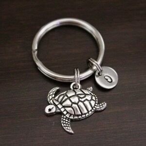 May include: Silver key chain with a turtle charm and a letter 'O' charm.