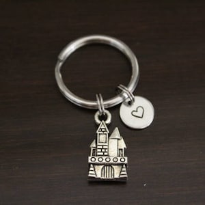 May include: Silver keychain with a small castle charm and a heart charm. The castle charm has a detailed design with windows and a door.