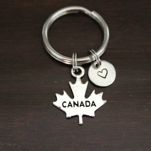 May include: Silver keychain with a maple leaf charm that says "CANADA" and a small heart charm.