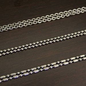 May include: Three different types of silver chains, labeled C3, C4, and C5. The chains are laid out horizontally on a dark brown surface.